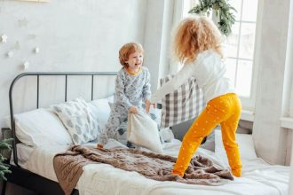 enfants jouant avec des coussins sur un lit douillet