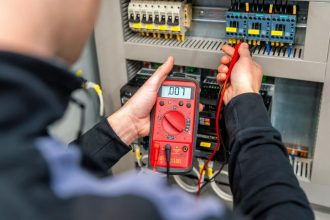 Technicien mesurant un tableau électrique Schneider Electric sur un chantier